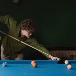 man in green long sleeve shirt playing billiard