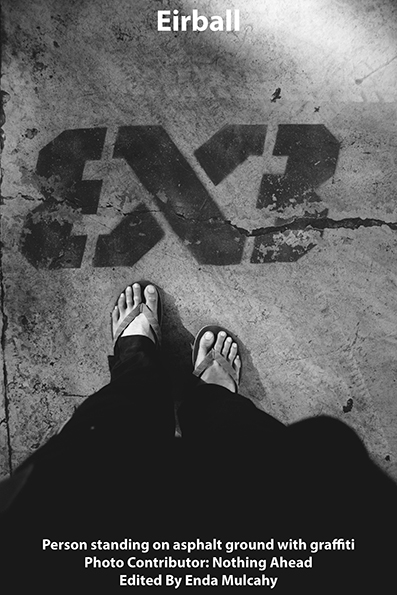 Person standing on asphalt ground with graffiti